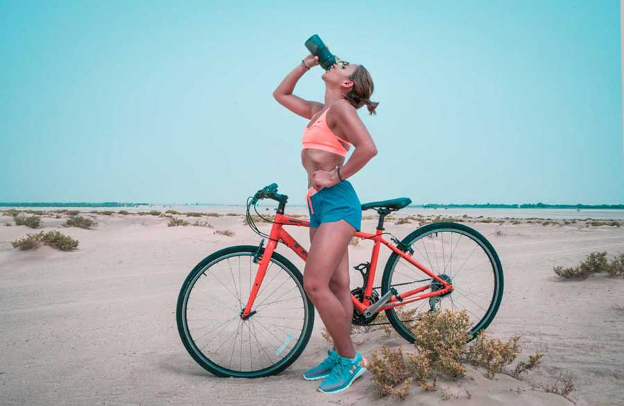 Eine Frau trinkt Wasser auf dem Fahrrad